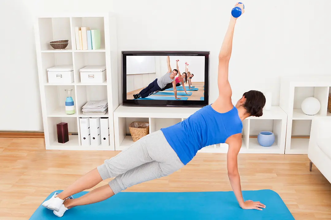 Woman working out in front of TV in home gym with white walls