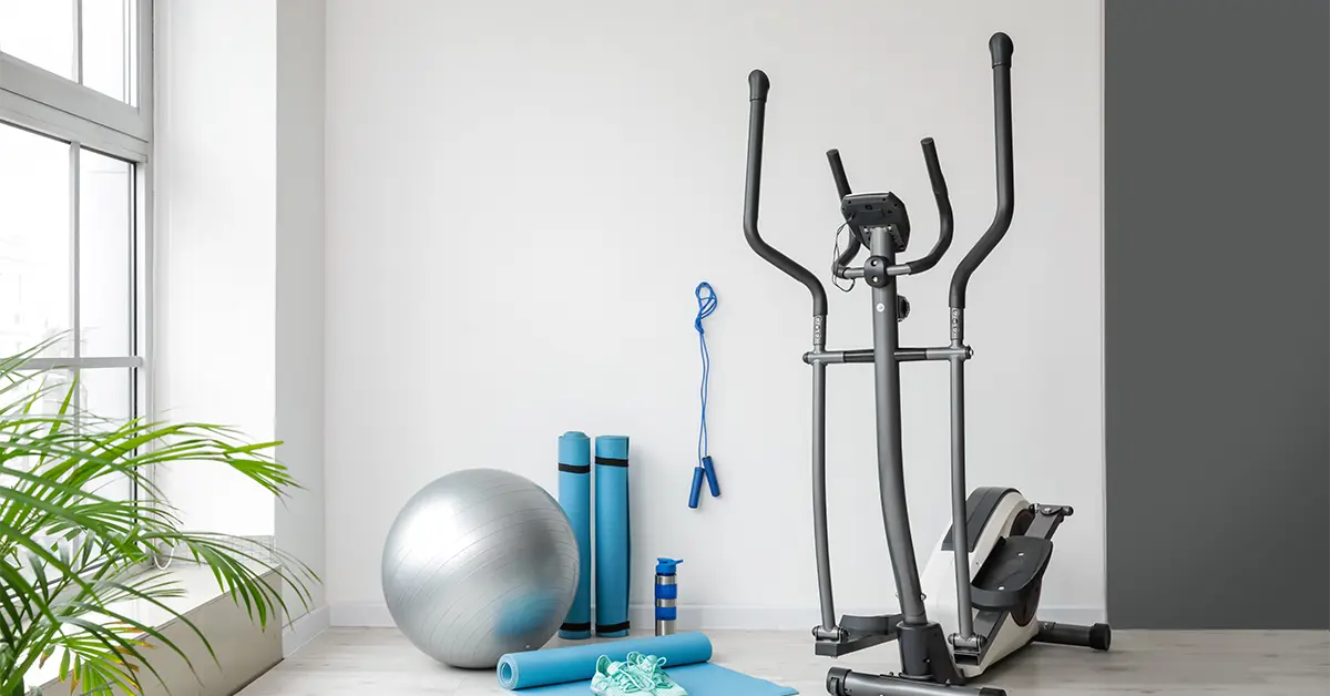 Exercise ball, yoga mats, sneakers, and elliptical machine in home gym